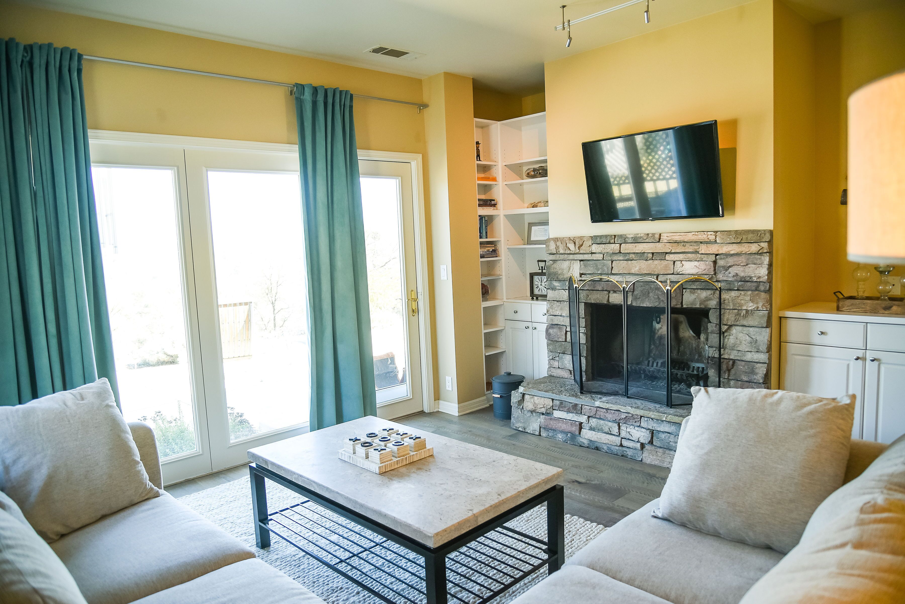 TV room with 2nd wood burning fireplace, sleeper sofa, and door to back patio