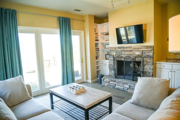 TV room with 2nd wood burning fireplace, sleeper sofa, and door to back patio