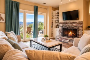 A living room with a fireplace, a sofa set, a coffee table, and a television mounted on the wall.