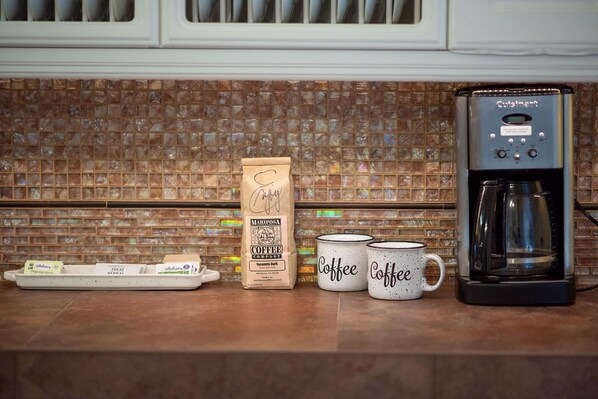 A coffee maker, a coffee pod tray, a coffee bag, and two coffee mugs on a kitchen counter. - Sierra Ranch - Yosemite Views, Cozy Fireplaces & Stunning Sunsets (Mariposa)