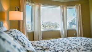 Une chambre à coucher avec un lit, une lampe et une fenêtre avec des rideaux.