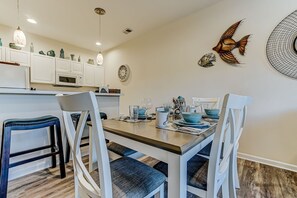 A dining area with a wooden table set for four, white chairs, and decorative wall art.