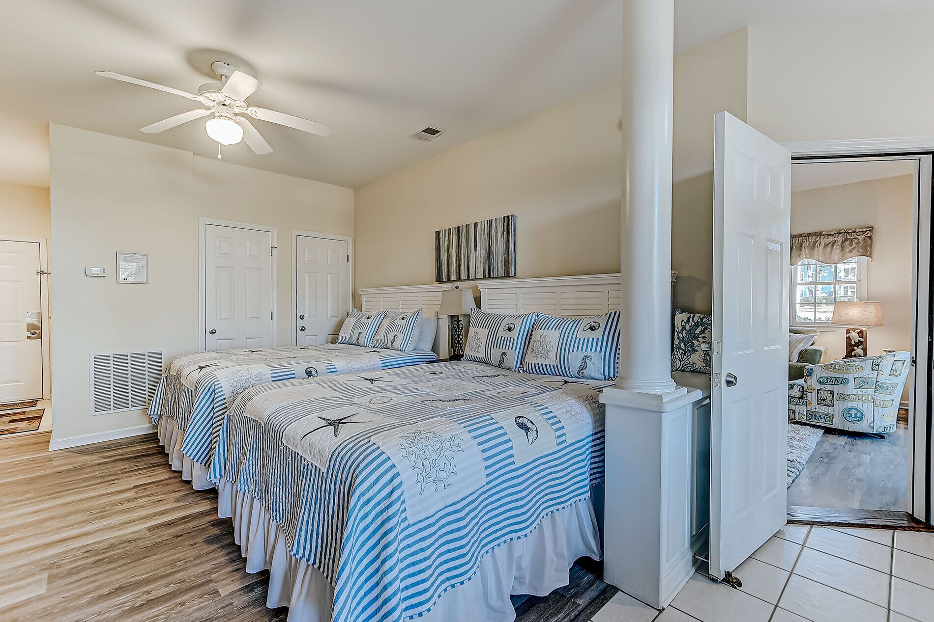 A bedroom with a large bed, a ceiling fan, and a door leading to another room.