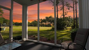Ein Wintergarten mit Blick auf einen Golfplatz bei Sonnenuntergang.