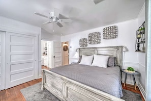 A bedroom with a bed, a ceiling fan, and decorative wall art.