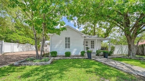 A single-story house with a front yard, a small porch, and a garage. - Romantic-Steps To Main-FirePit! (Fredericksburg)