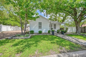 A single-story house with a front yard, a driveway, and a white fence.