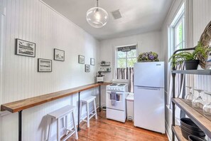 Una cocina funcional con electrodomésticos blancos, una barra de bar de madera y fotografías enmarcadas en la pared.