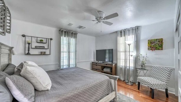 A bedroom with a bed, a TV, a chair, and a ceiling fan. - Romantic-Steps To Main-FirePit! (Fredericksburg)