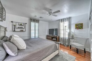 A bedroom with a bed, a TV, a chair, and a ceiling fan.