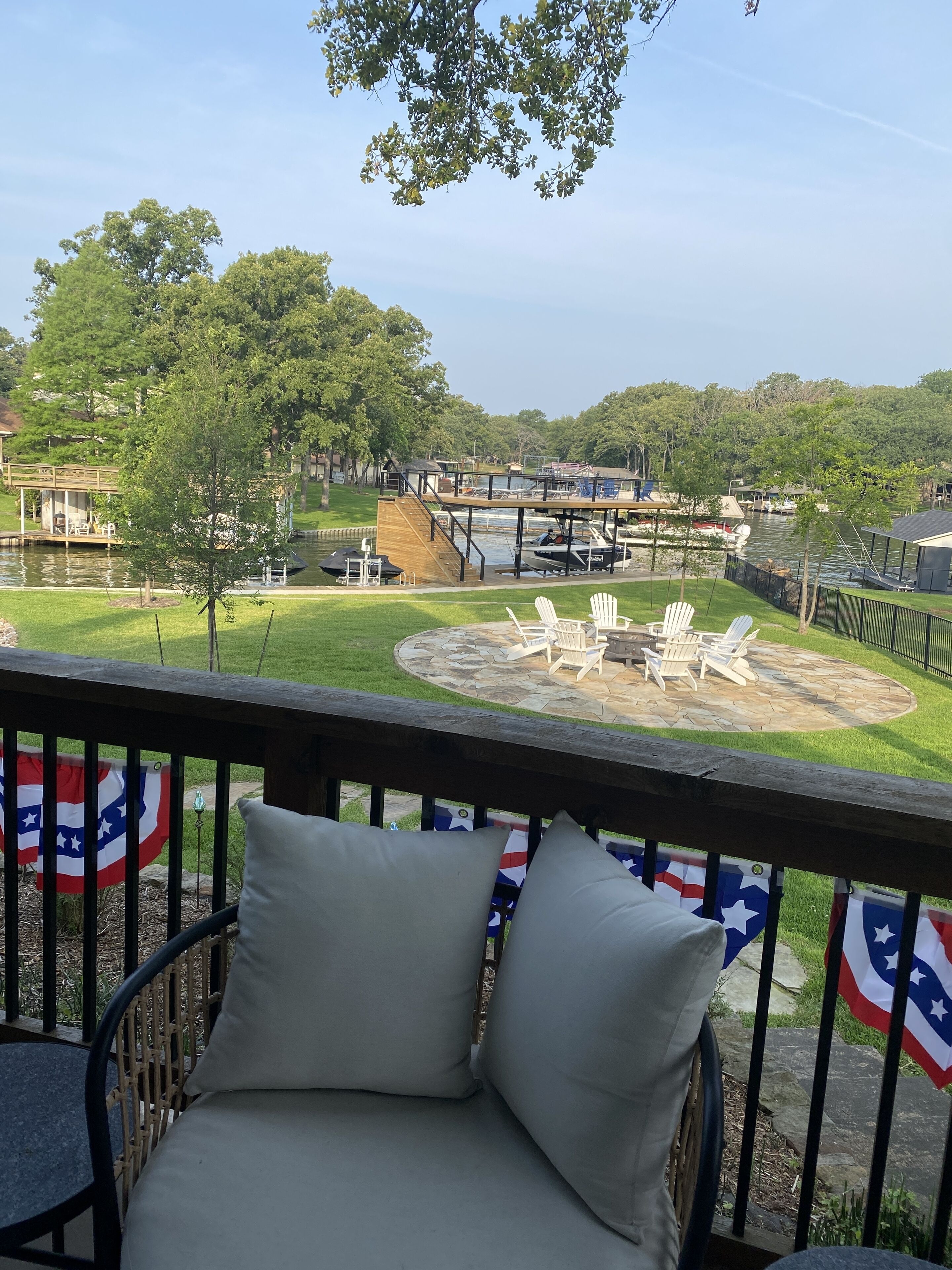 Une terrasse avec vue sur un lac, des sièges d’extérieur et des drapeaux américains.