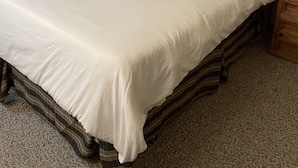 Une chambre à coucher avec un grand lit, une tête de lit en bois, une table de chevet en bois, une lampe et un miroir sur le mur.