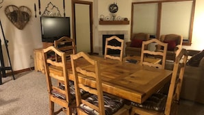 Un coin repas avec une table et des chaises en bois, un téléviseur et une cheminée.