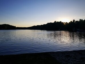 A calm lake at sunset with a silhouette of trees and a clear sky. - Cozy Blue Cottage With Access To All Sports Lake.  (Greenville)