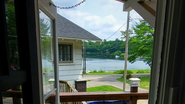 A wooden deck with a view of a lake and a house. - Cozy Blue Cottage With Access To All Sports Lake.  (Greenville)