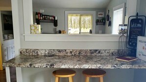 A kitchen with a 'GATHER' sign, two wooden stools, and a countertop. - Cozy Blue Cottage With Access To All Sports Lake.  (Greenville)