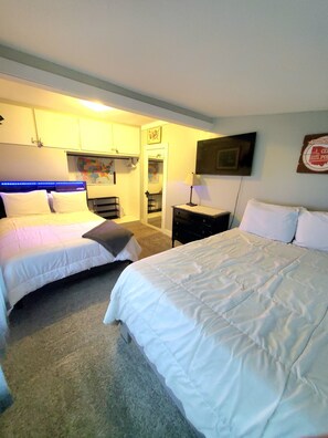 A hotel room with two beds, a map on the wall, a television, and a small table with a lamp. - Cozy Blue Cottage With Access To All Sports Lake.  (Greenville)