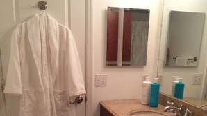 Un baño con lavamanos, espejo y artículos de aseo.