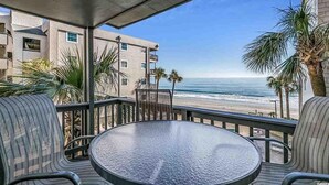 A balcony with a view of the ocean, furnished with a table and chairs, overlooking a beach. - Great Location, Family Friendly.  Beach Front 3Bedroom 3Bath Sleeps 10 (Murrells Inlet)
