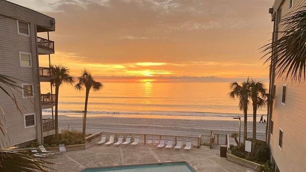 A pool area with lounge chairs and a view of the ocean at sunset. - Great Location, Family Friendly.  Beach Front 3Bedroom 3Bath Sleeps 10 (Murrells Inlet)