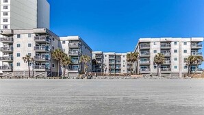 A beachfront hotel with multiple-story buildings, balconies, and palm trees. - Great Location, Family Friendly.  Beach Front 3Bedroom 3Bath Sleeps 10 (Murrells Inlet)