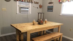 A wooden dining table with a bench, a window with blinds, and wall decorations including a sign with motivational phrases. - Hilltop Cabin at Wood Creek Lake (London)