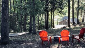 A forested area with a wooden cabin in the background, surrounded by tall trees. - Hilltop Cabin at Wood Creek Lake (London)