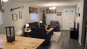 A cozy living room with a wooden table, two sofas, a Christmas tree, and a fireplace. - Hilltop Cabin at Wood Creek Lake (London)