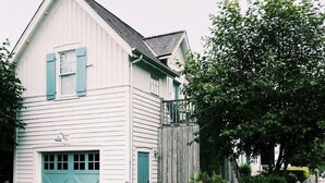 A two-story white building with blue shutters and a wooden fence. - Vintage-inspired cottage in Seabrook, sleeps 7 (Pacific Beach)