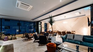 A modern living room with a sofa, chairs, a coffee table, and a large window with blinds. - Hotels One (Wanju)