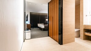 A modern hotel room with a wooden wardrobe, a bed, a desk, and a bathroom with a toilet and sink. - Hotels One (Wanju)