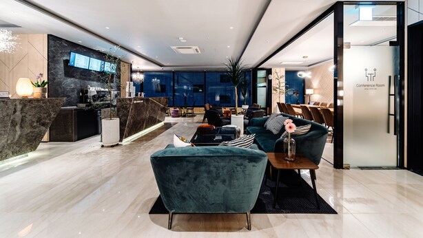 A modern hotel lobby with a reception desk, seating area, and a conference room. - Hotels One (Wanju)