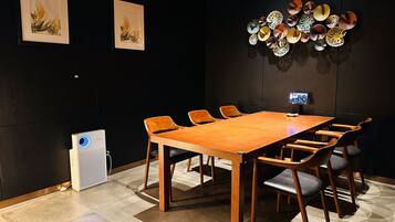 A conference room with a long wooden table, six chairs, and two framed botanical prints on the wall.