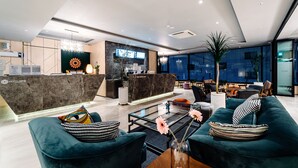 A modern hotel lobby with a reception desk, seating area, and large windows. - Hotels One (Wanju)
