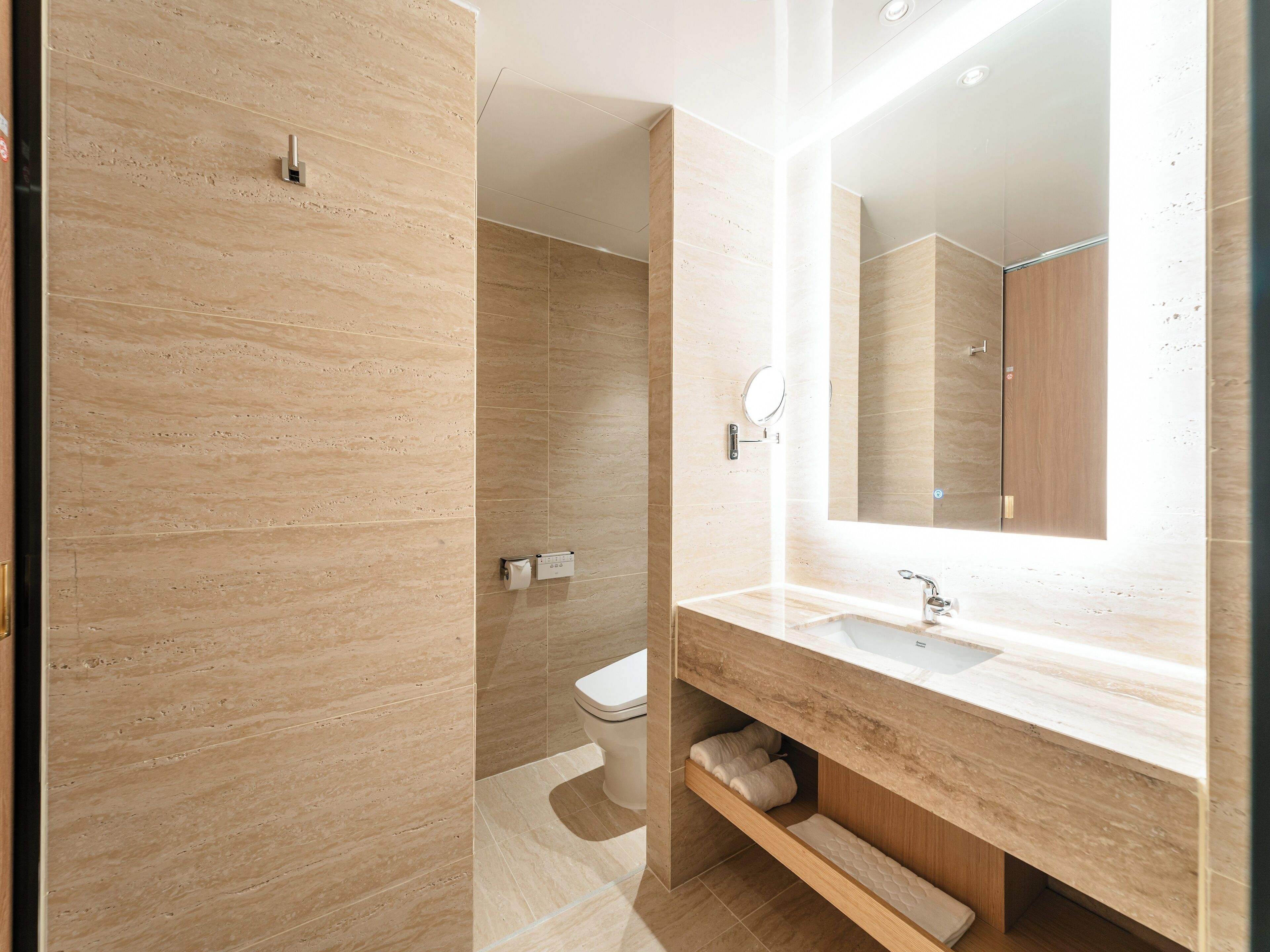 A modern bathroom with a marble vanity, a large mirror, and a toilet.