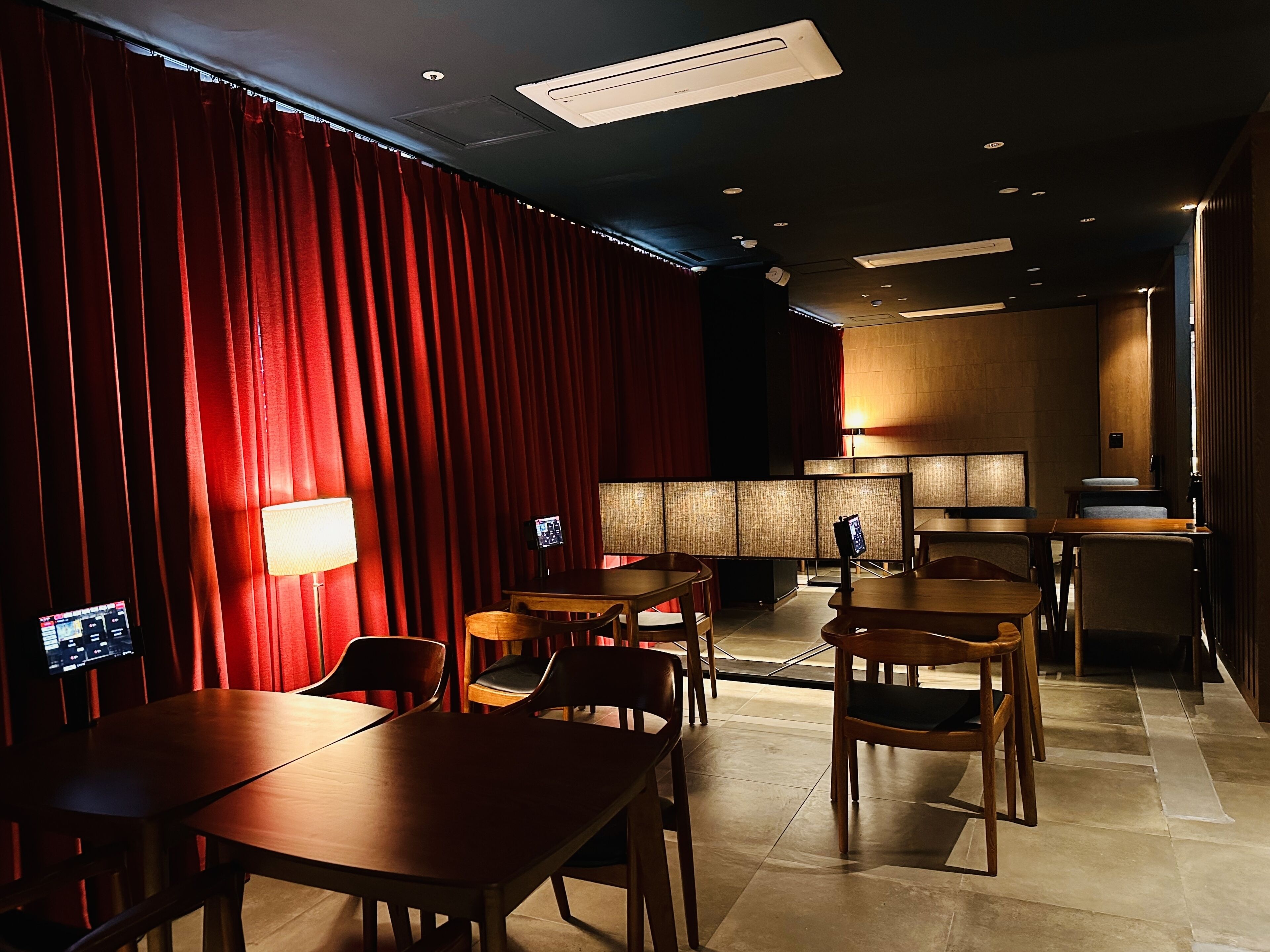 A hotel room with a red curtain, wooden furniture, and a modern design.