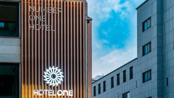 A modern hotel facade with vertical wooden slats and illuminated signage for Number One Hotel.