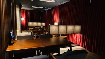 A conference room with a long table, chairs, and a screen.