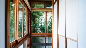 A corridor with wooden flooring and large sliding doors on both sides, leading to a view of greenery outside. - Hakonowa Hot spring inn (Hakone)