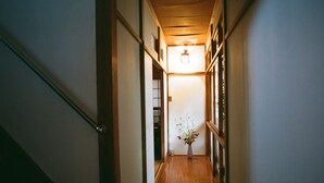 A narrow hallway with wooden flooring and a vase with flowers at the end. - Hakonowa Hot spring inn (Hakone)
