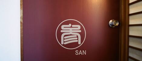 A maroon door with a white logo and the word "SAN" below it.