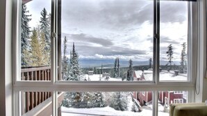 Una stanza con un'ampia finestra che si affaccia su un paesaggio innevato con alberi e edifici.