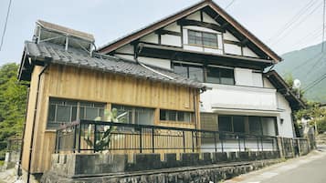 Una casa japonesa tradicional con fachada de madera, un muro de piedra delantero y un garaje.