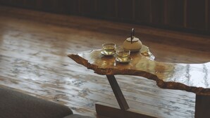 Uma mesa de madeira com tampo de vidro, uma tigela pequena e dois copos.