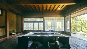 Une pièce de style japonais traditionnel, avec un sol recouvert de tatamis, une basse table en bois et une vue sur un jardin à travers des panneaux coulissants en papier.