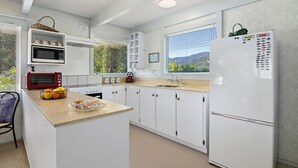 A modern kitchen with white cabinetry, a microwave, a toaster, a sink, and a refrigerator. - Pukenui Paradise - Havelock Holiday Home (Havelock)