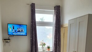 Una habitación con cama, escritorio, silla, televisor y armario.