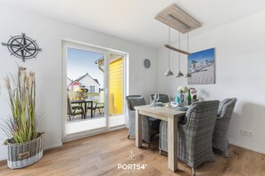 Zona pranzo con sedie in vimini, un tavolo di legno e vista all'esterno tramite una porta vetrata.
