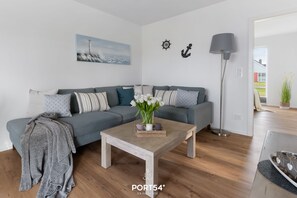 A modern living room with a grey sofa, a wooden coffee table, and a floor lamp.