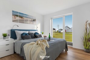 Una camera da letto con un letto grande, un comodino, una finestra che dà su un panorama esterno e un'opera d'arte appesa al muro.